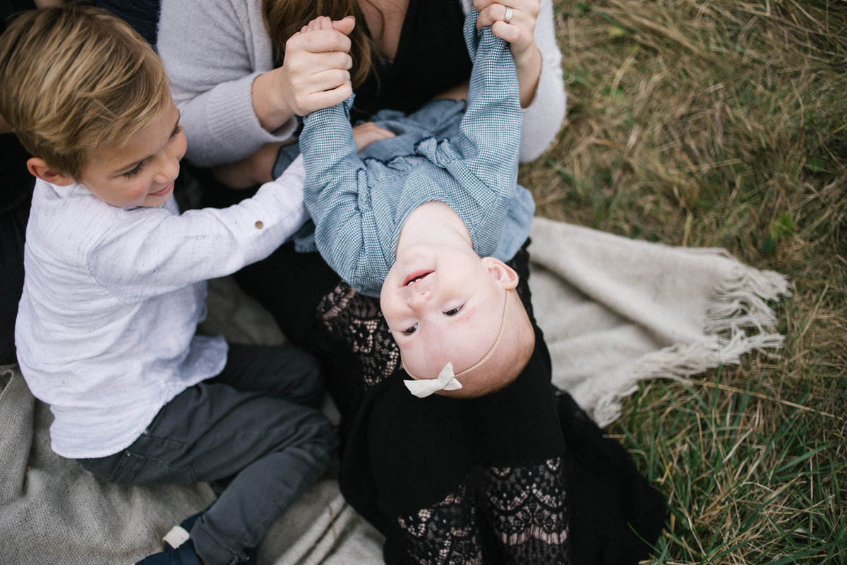 Mother and son tickling baby sister during family session with Elle Baker Photography
