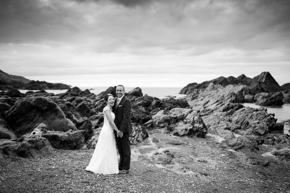 Black and white wedding photo of couple on beach at Tunnels Beaches