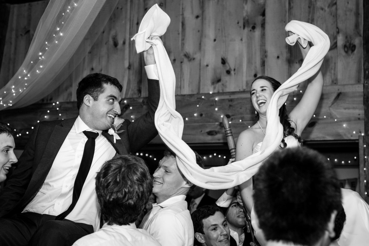 The bride and groom are celebrated with the horah dance at their reception at Clarks Cove Farm in Maine