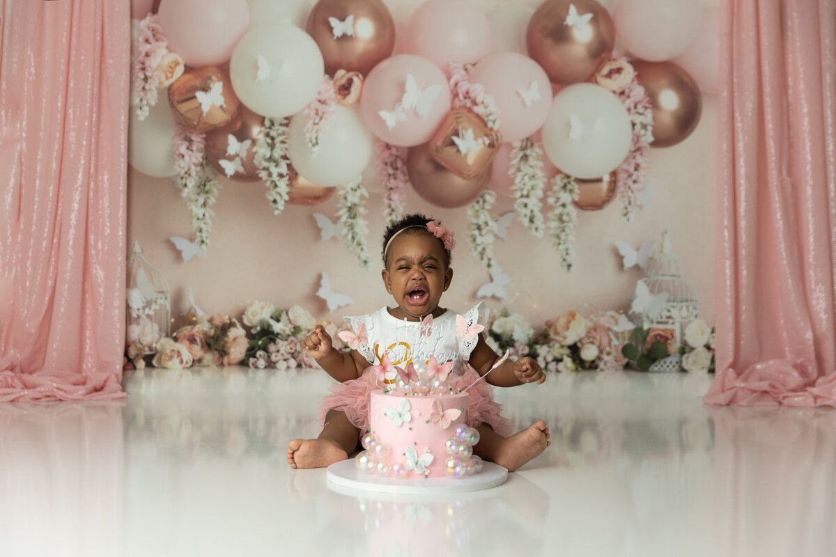 A young toddler cries during her photo session in a pink dress
