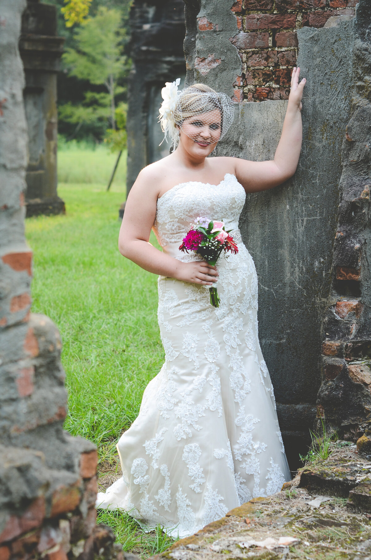 Beautiful bridal portrait photography: bride with birdcage veil stands among the ruins of Windsor Plantation in Mississippi