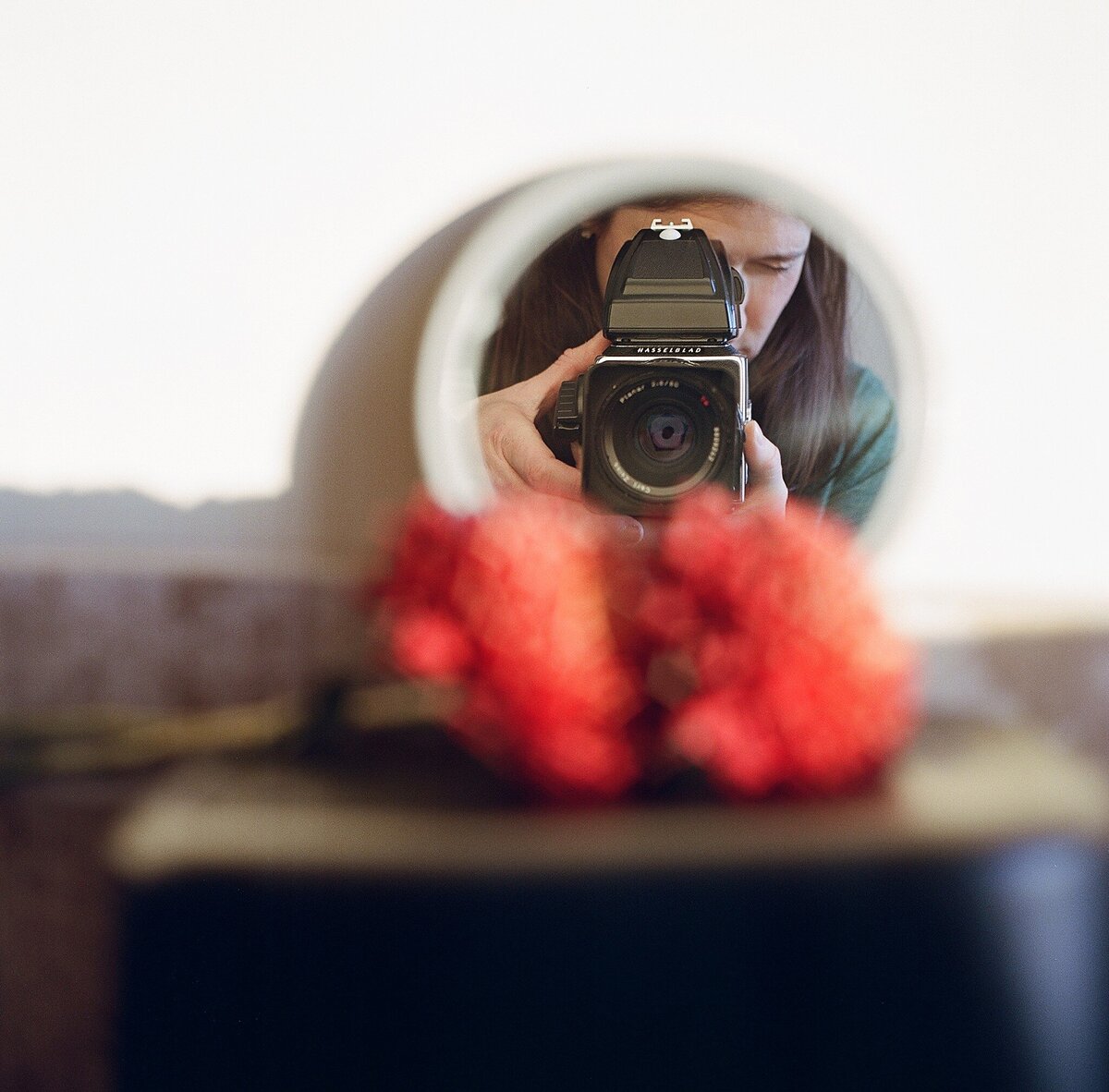 photographer reflection in round mirror holding hassleblad film camera