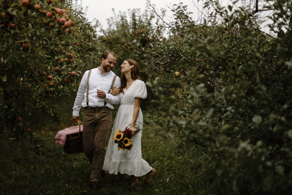 a couple walking in an apple orchard