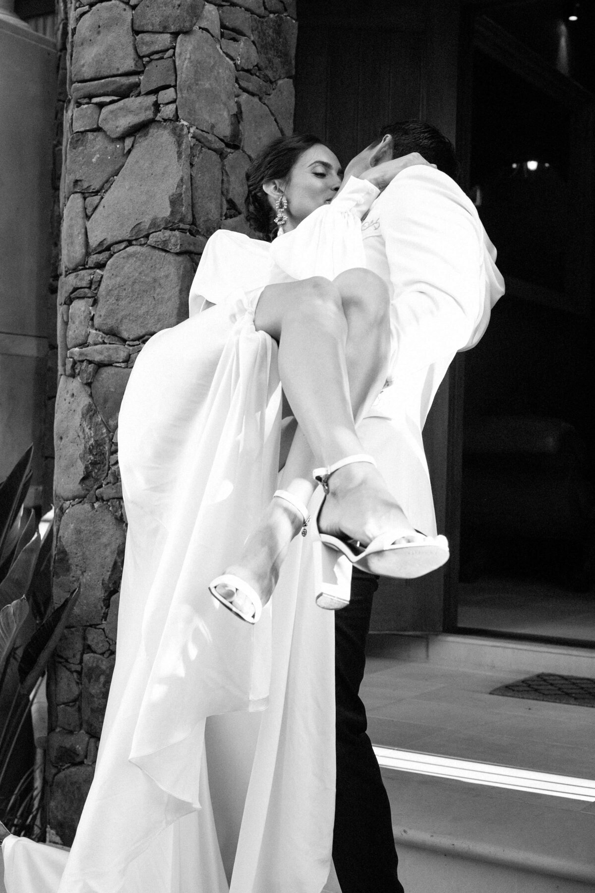 Bride wearing long silk wedding dress kissing groom on steps