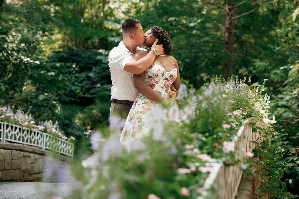 a couple shares a kiss during their engagement session at the botanical gardens