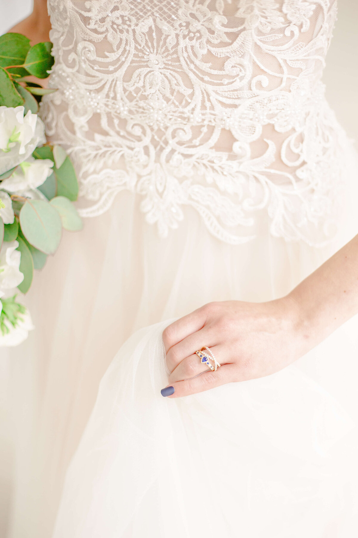 Close-up-of-bridal-gown-rings-wedding-nails-bouquet