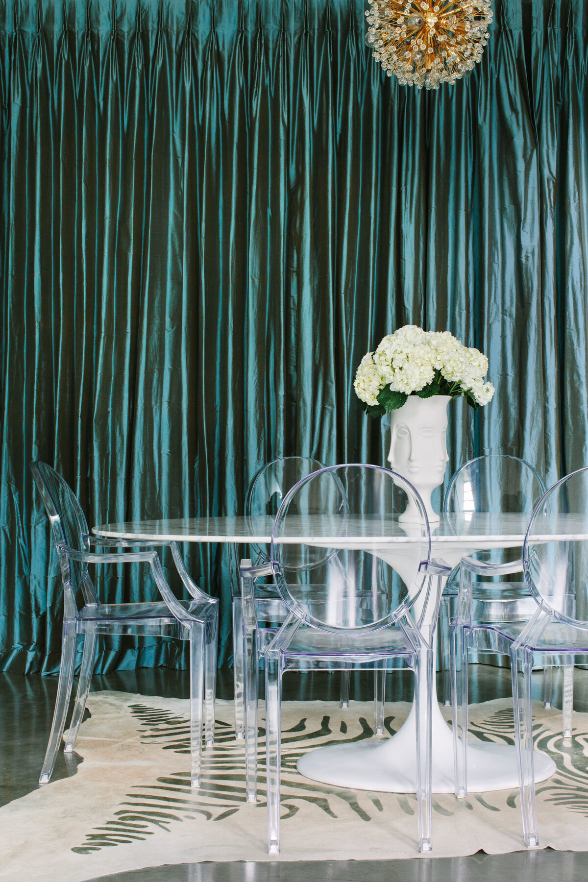 Marble Tulip table with Kartell Ghost chairs and metallic zebra rug