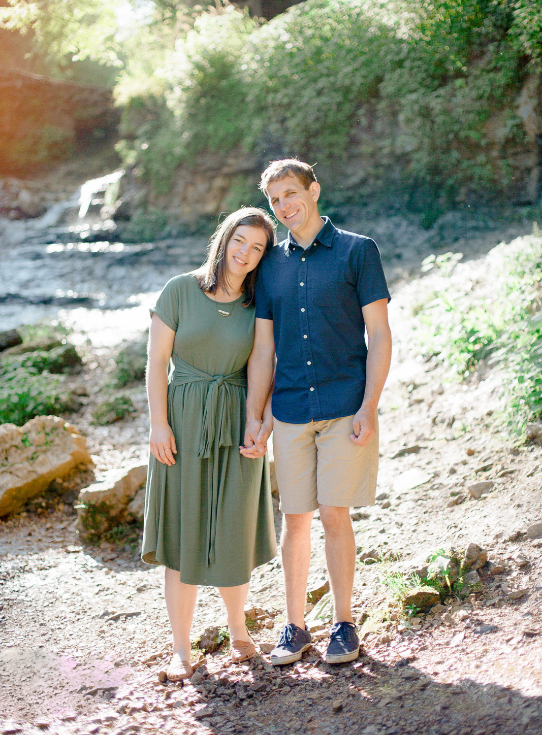 willow river state park waterfall background as couple stands hand in hand