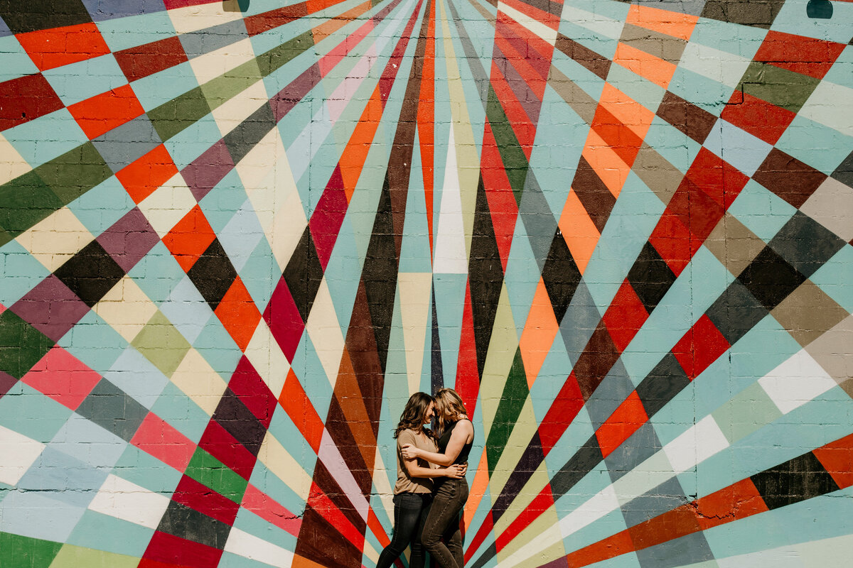 lesbian couple standing together in front of a colorful wall in downtown Albuquerque
