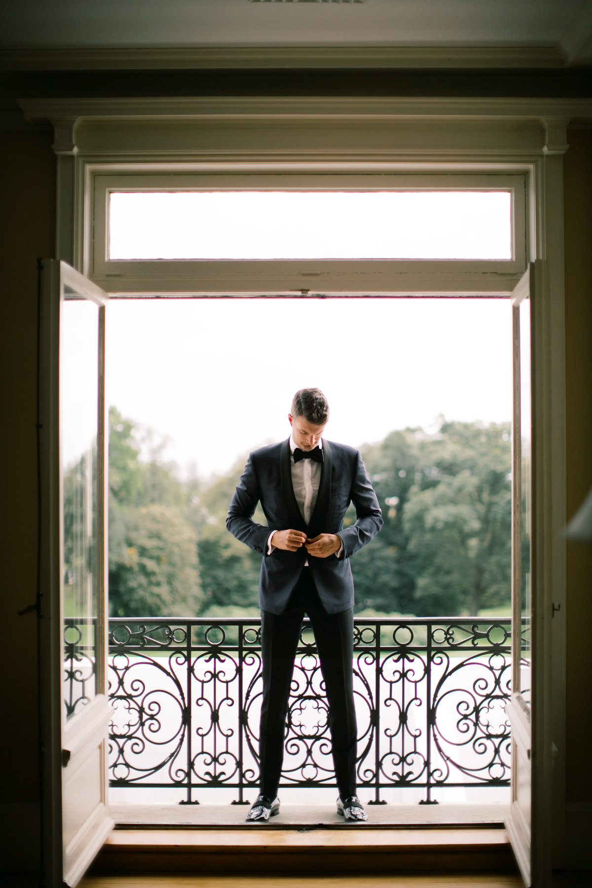 groom buttoning tuxedo jacket during groom portraits