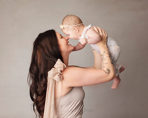 Mother holding baby close to her nose and smiling with greensburg studio outfits.