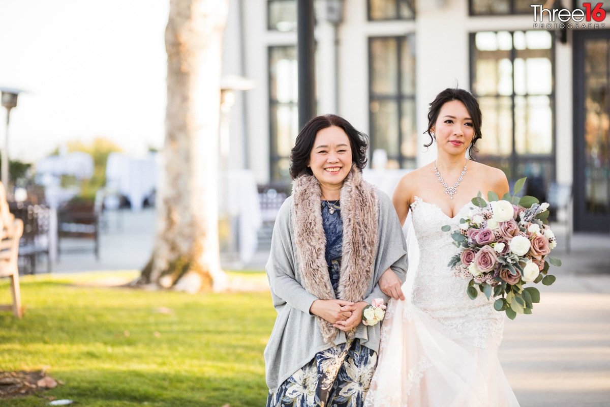 Bride walks arm in arm with her mother