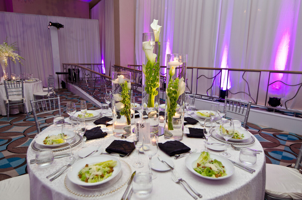 Wedding reception tables with chairs, dinnerwares, candles and floral centerpieces
