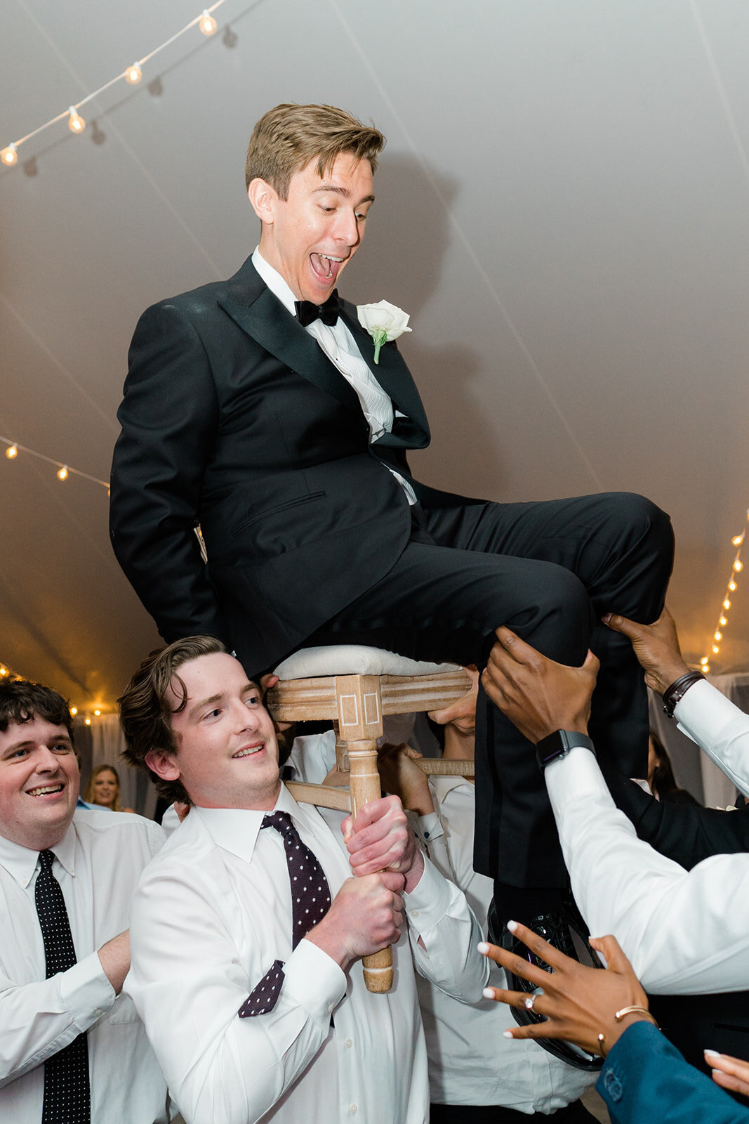 Wedding guests lift up groom in a chair on the dance floor at Bradley Estate summer wedding. East Coast Destination Wedding Photographer. Kailee DiMeglio Photography.