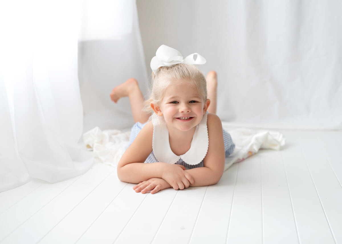 Family session of little girl laying down and smiling