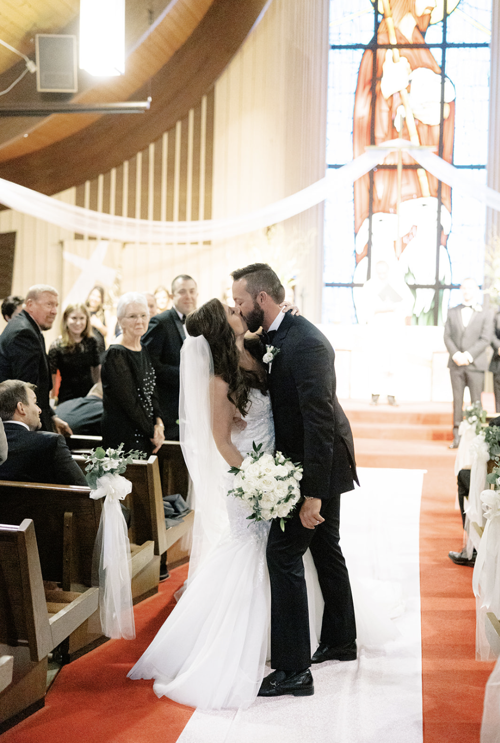 Chicago bride and groom stop midway down aisle after exchanging vows to kiss in Chicago wedding.