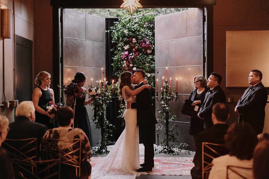 Intimate and moody wedding ceremony with tall black candelabras and a floral wall at JM Cellars.