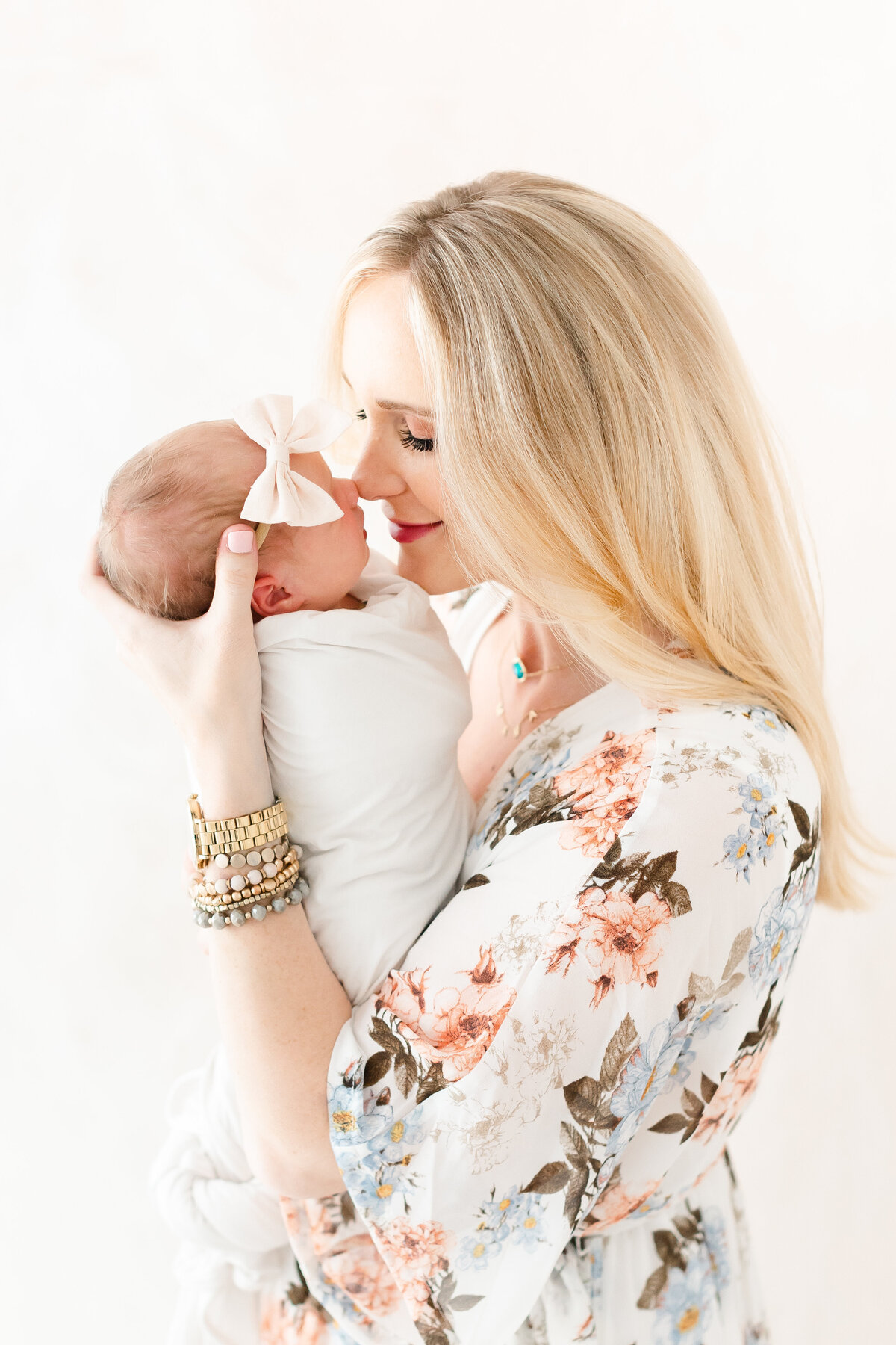 A DC newborn photography image of a mother holding her baby nose to nose in front of a hand-painted canvas backdrop