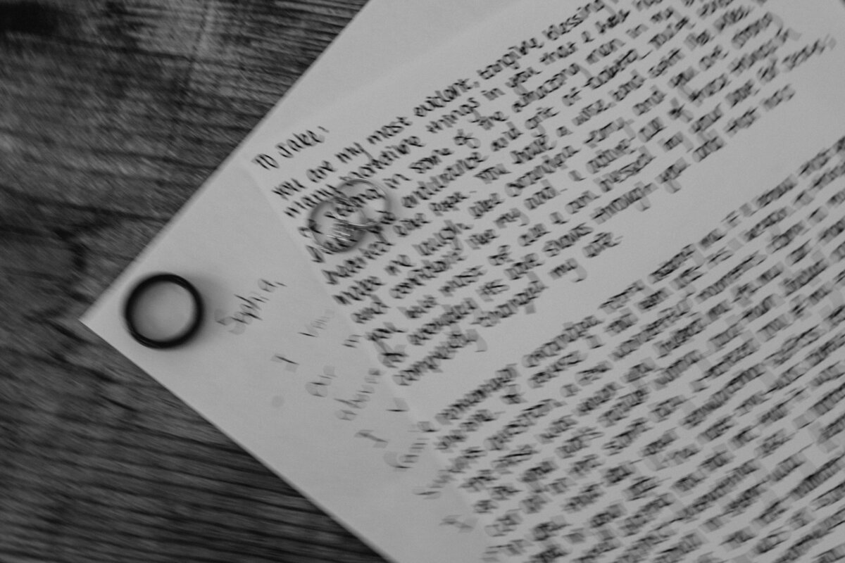 Wedding rings sit atop handwritten vows the bride and groom wrote. Captured in a blurry, documentary style.