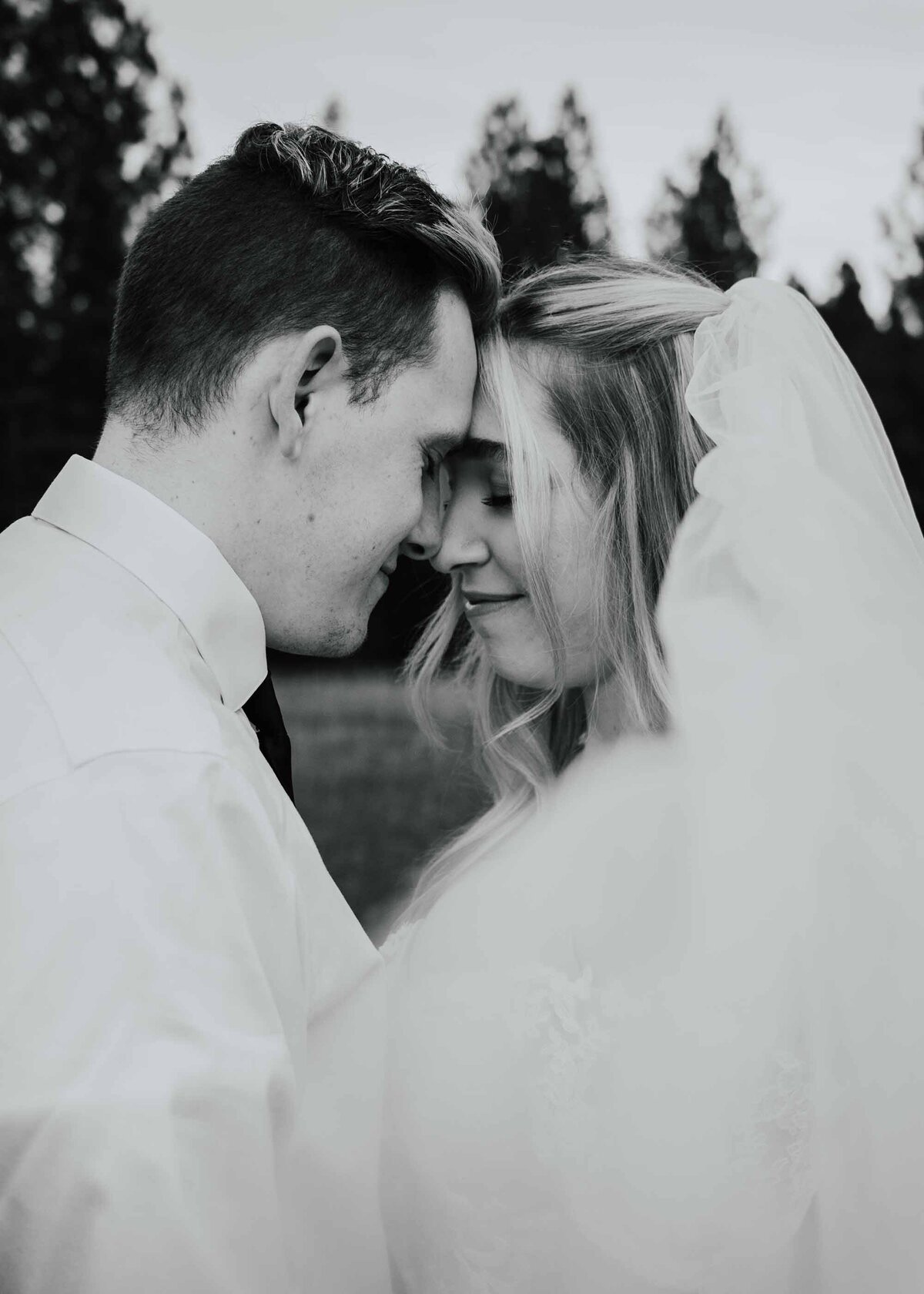 Maddie Rae Photography black and white close up of bride and groom touching foreheads. the veil is pulled at an angle in front of the camera