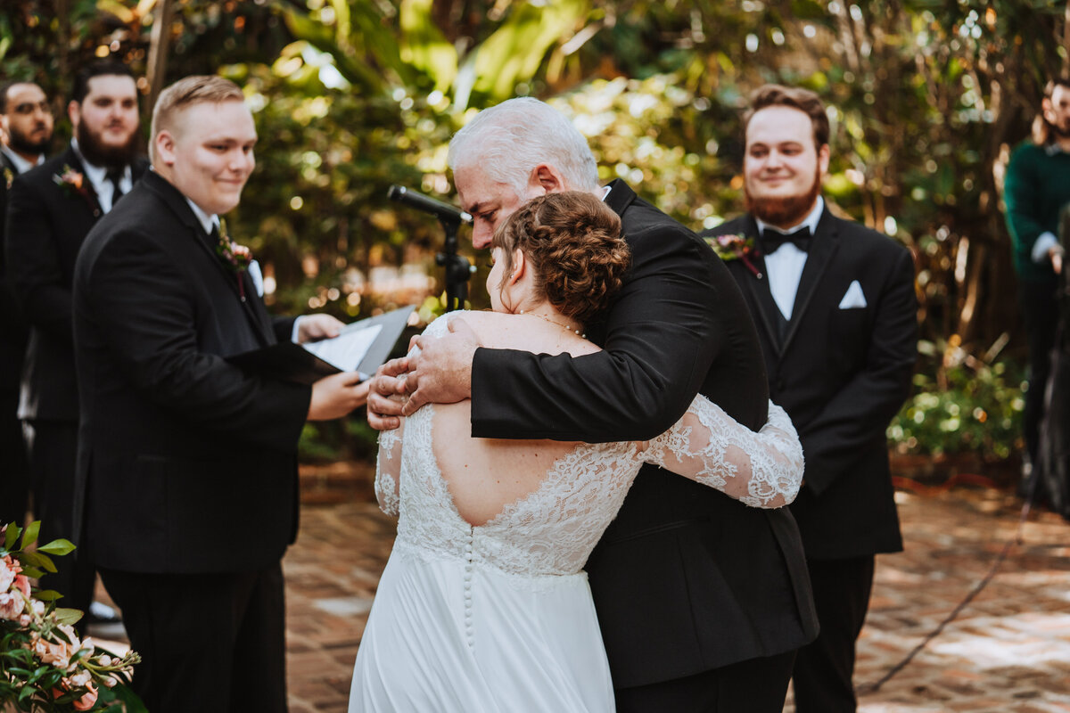 father of bride hugging bride and giving her away at ceremony at sunken gardens in st pete florida