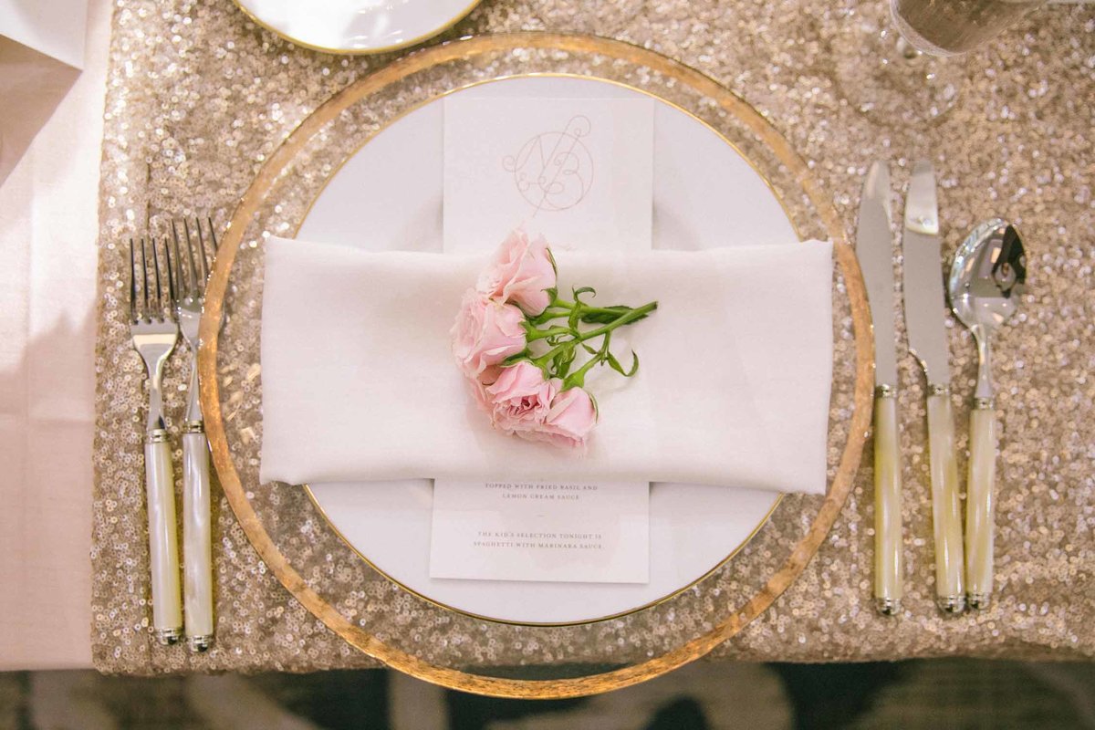 Pink spray rose napkin bloom on gold place setting