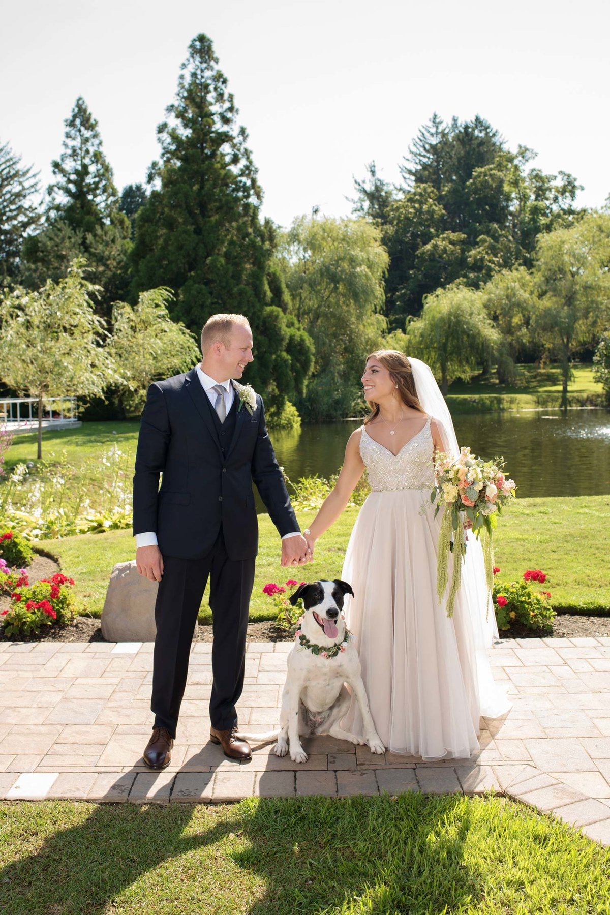 Bride and groom with their dog holding hands outside at Flowerfield