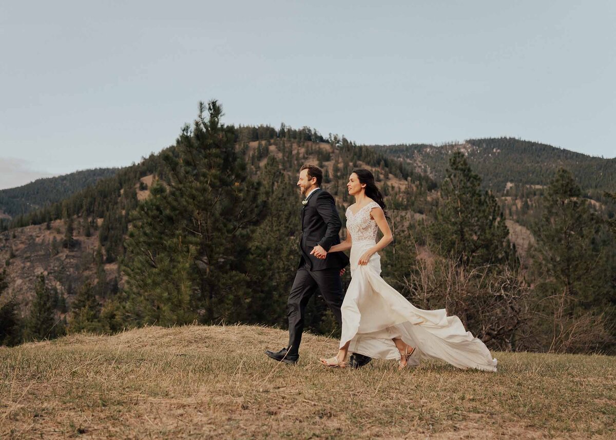 MaddieRaePhotography wedding couple running, brides dress flowing behind her, mountains in the background