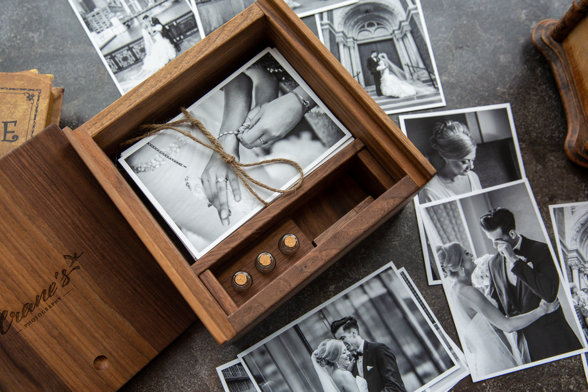 Wooden keepsake wedding box on a table with prints spread around the box.