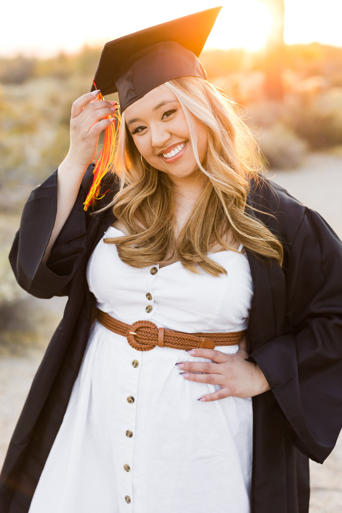 high school senior girl posing with cap and gown in the desert