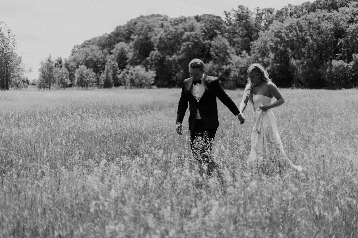 bride and groom walking together in a field