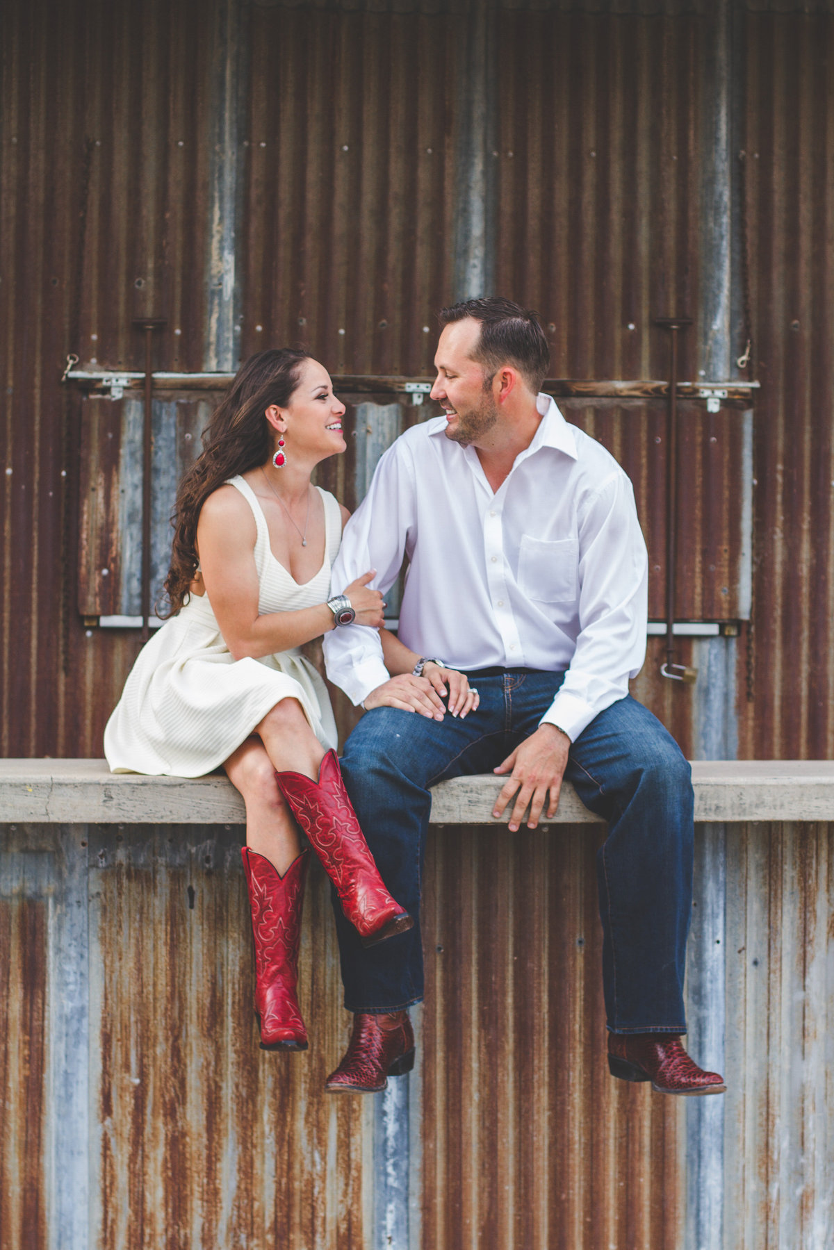 Man and woman sitting on bar top at the Blue Start on a metal wall. Woman is wearing red cowboy boots.