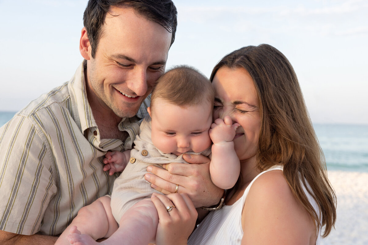 Parents smiling while holding up their baby