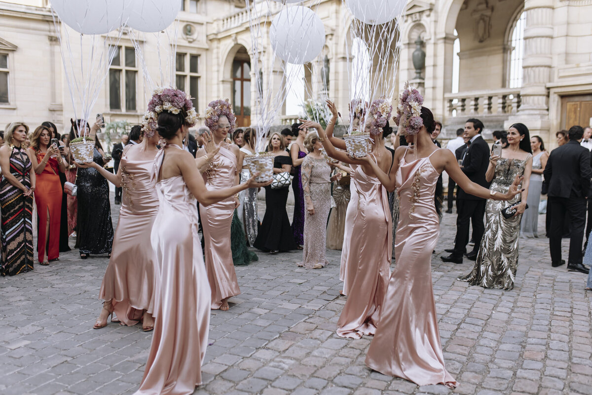 Paris Destination Wedding at Chateau de Chantilly by Alejandra Poupel Events artists wearing pink dresses and holding white balloon 3 