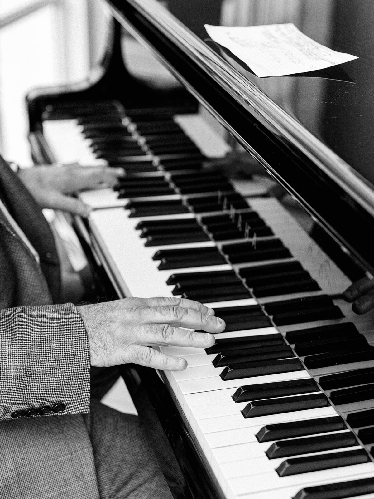 Piano and hands playing it in a black and white photo
