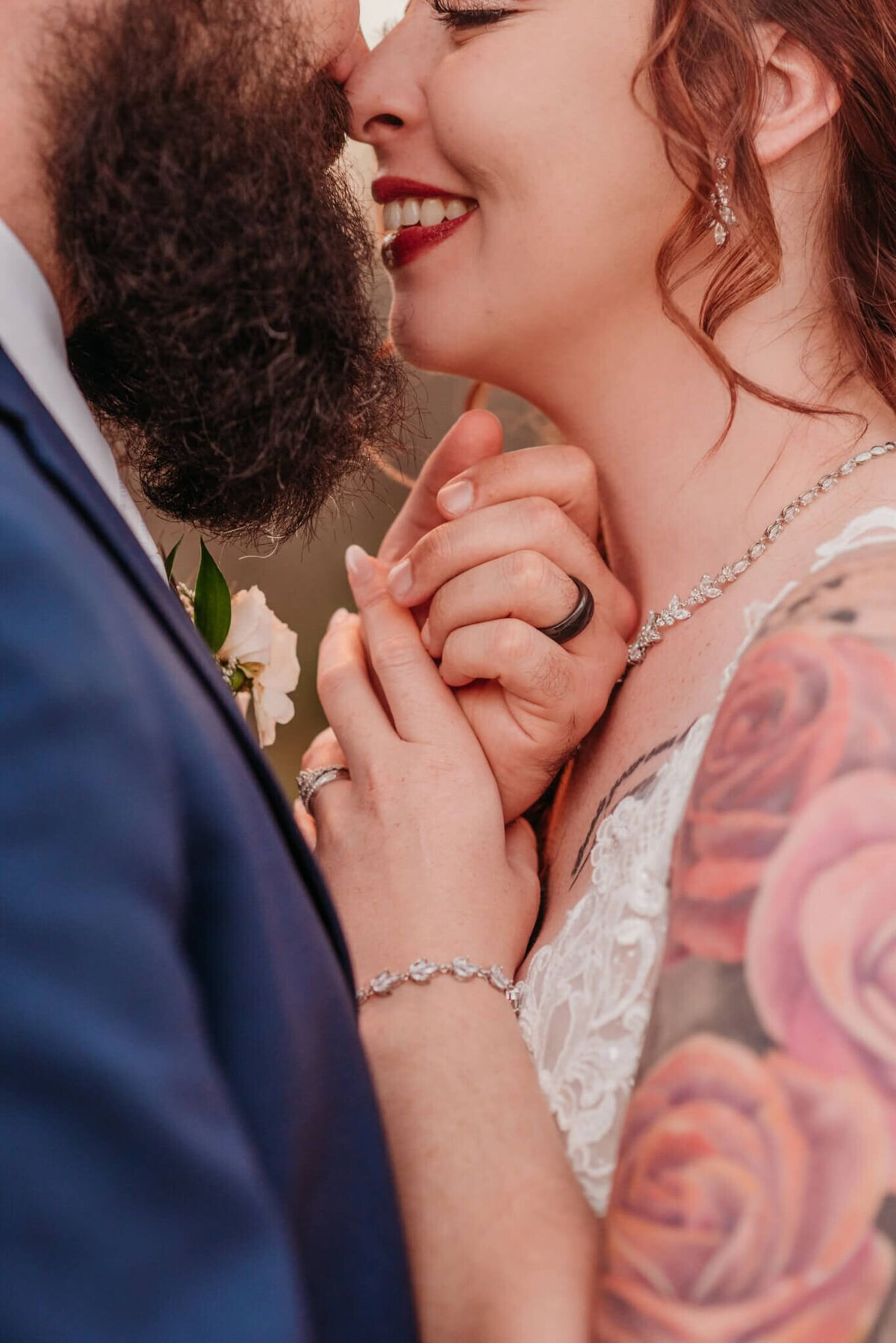 Photo of a bride and groom about to kiss while holding hands and showing off their wedding rings