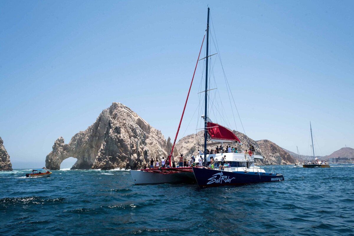 A sailboat offers a water activity experience to event participants as it sails past the arch in Cabo.