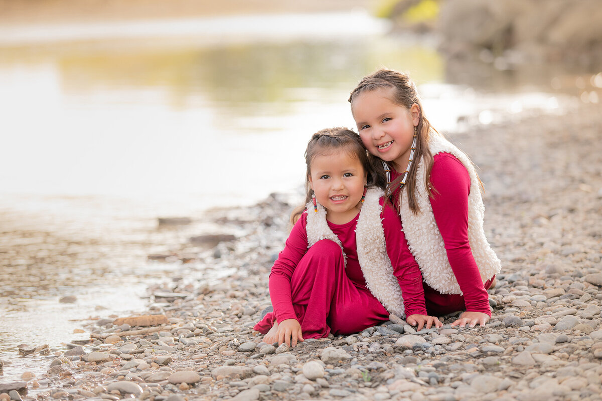 Pictures of sisters sitting next to the Yellowstone River at sunset.