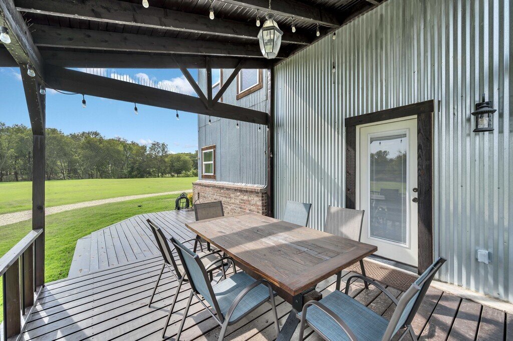 Covered deck with outdoor seating and beautiful view at this four-bedroom, four-bathroom vacation rental home and guest house with free WiFi, fully equipped kitchen, firepit and room for 10 in Waco, TX.