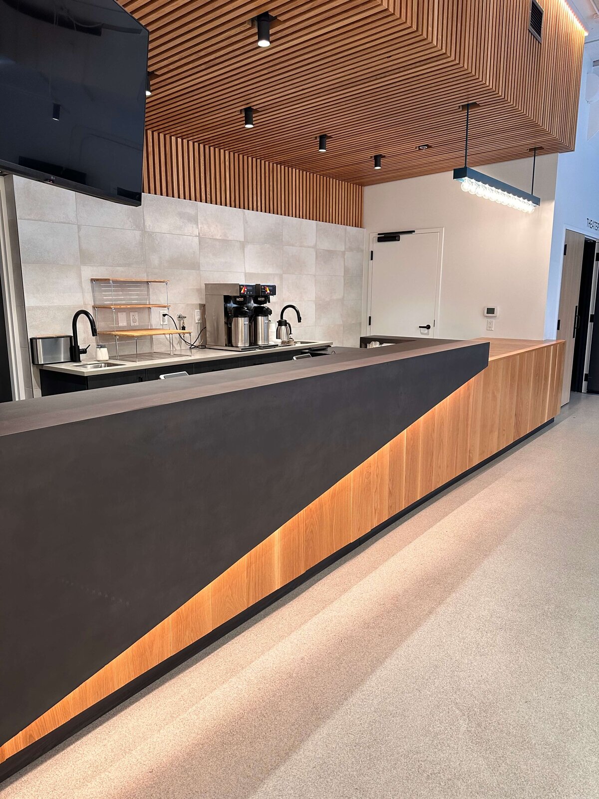 Backlit concrete countertop for concession stand for an event center feature terrazzo floors and fluted wood and accent lighting