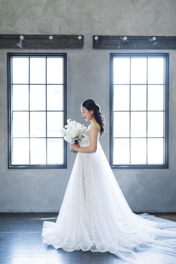 Lovely bride posing in a sparkly wedding dress holding a white bouquet.