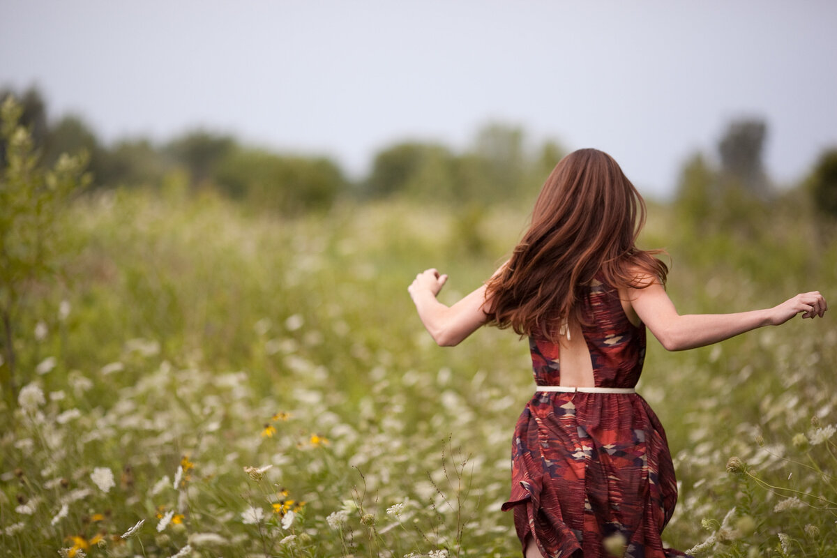 girl runs through field in red dress