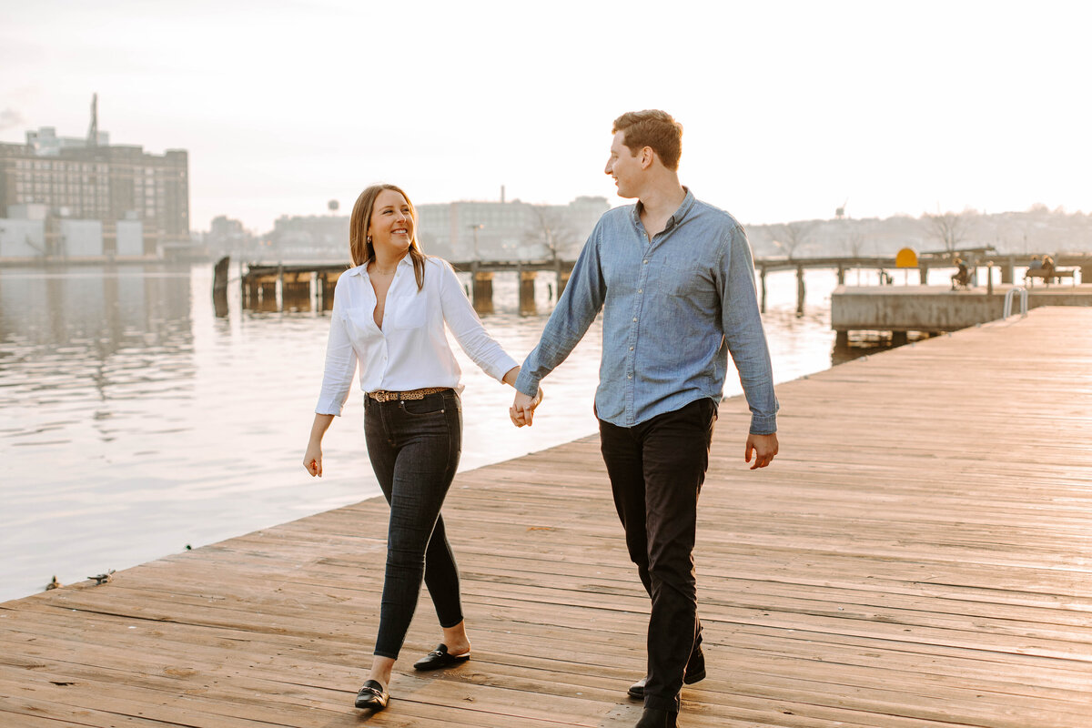 A couple is walking hand in hand on a pier in Baltimore