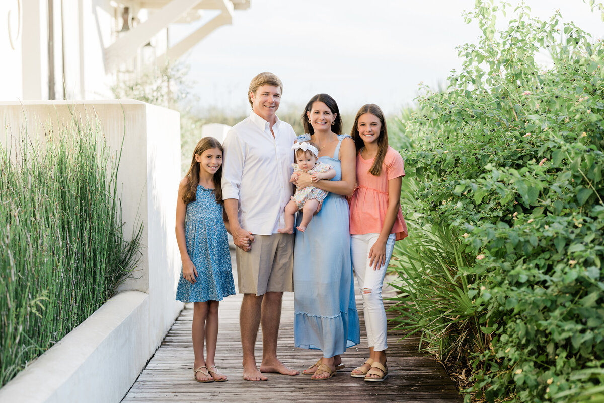 A family standing along a wooden path smiling