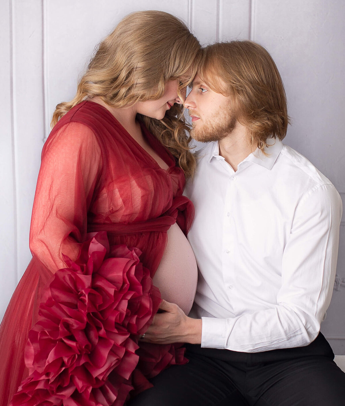 Couples maternity in studio canton with sheer red dress.