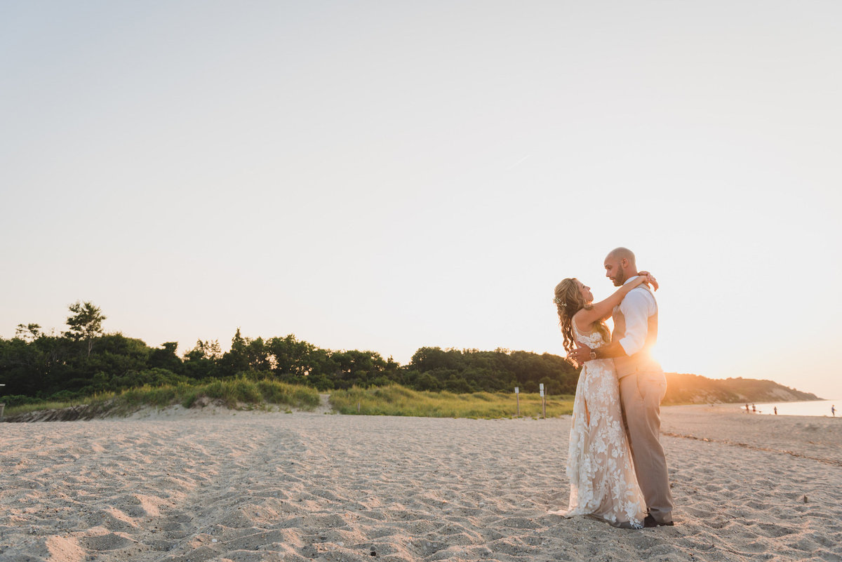 photo of bride and groom on the beach with sunsetting behind them from wedding at Pavilion at Sunken Meadow
