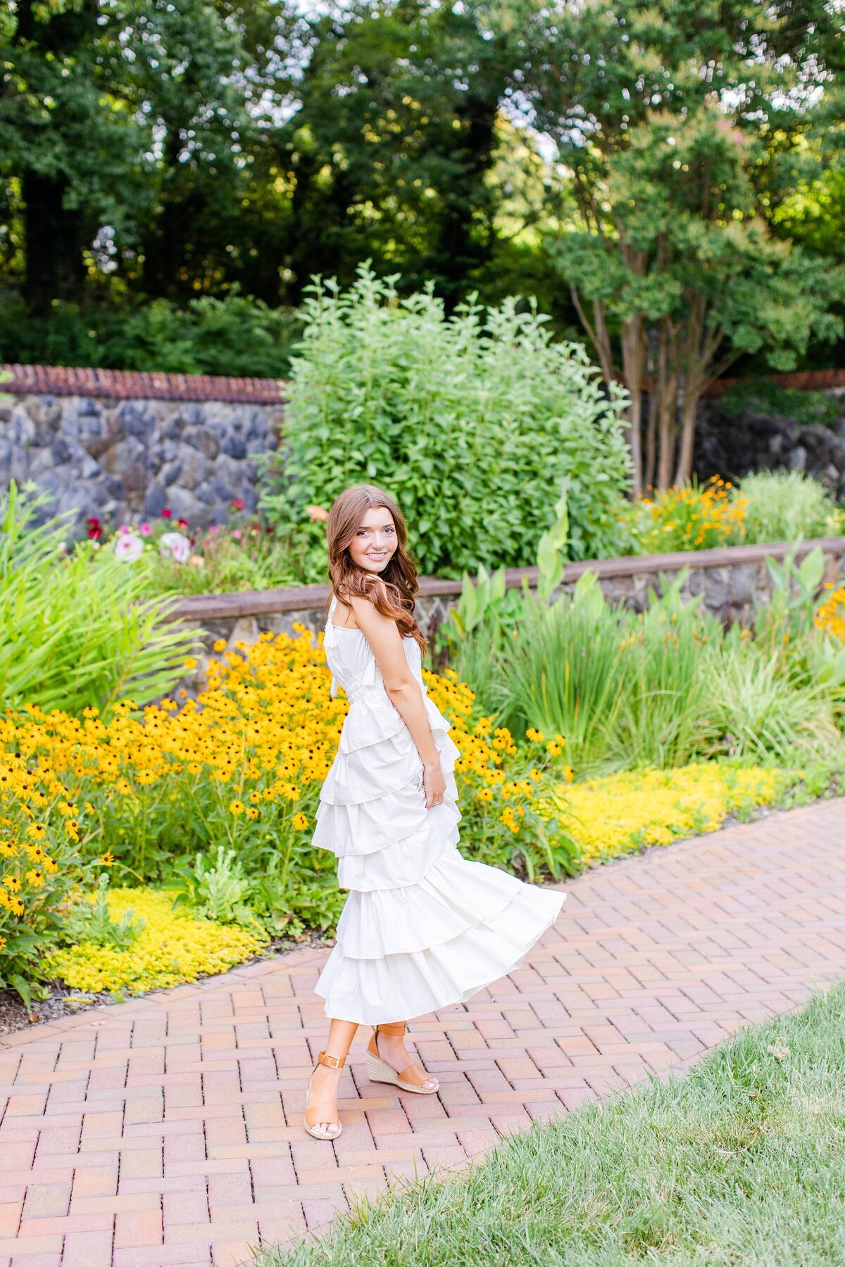 girl swinging white dress in front of yellow flowers