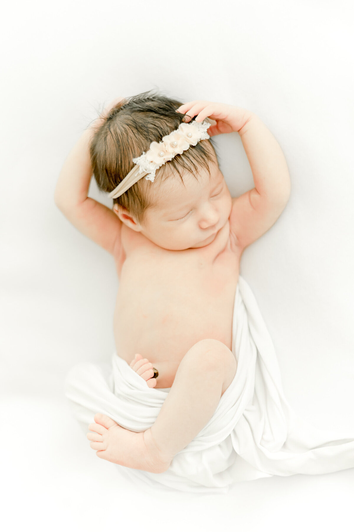 newborn girl in a pink headband sleeps In Kristie Lloyd’s Nashville newborn photographer studio