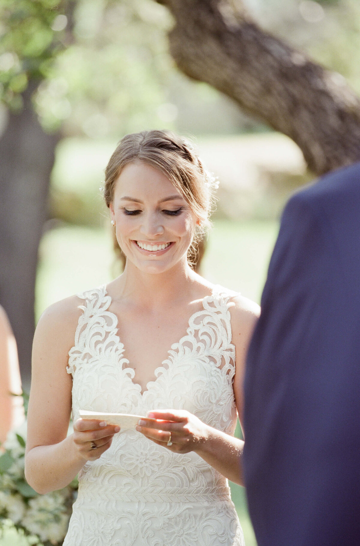 An exhilarated bride reads her wedding vows in an outdoor wedding venue.