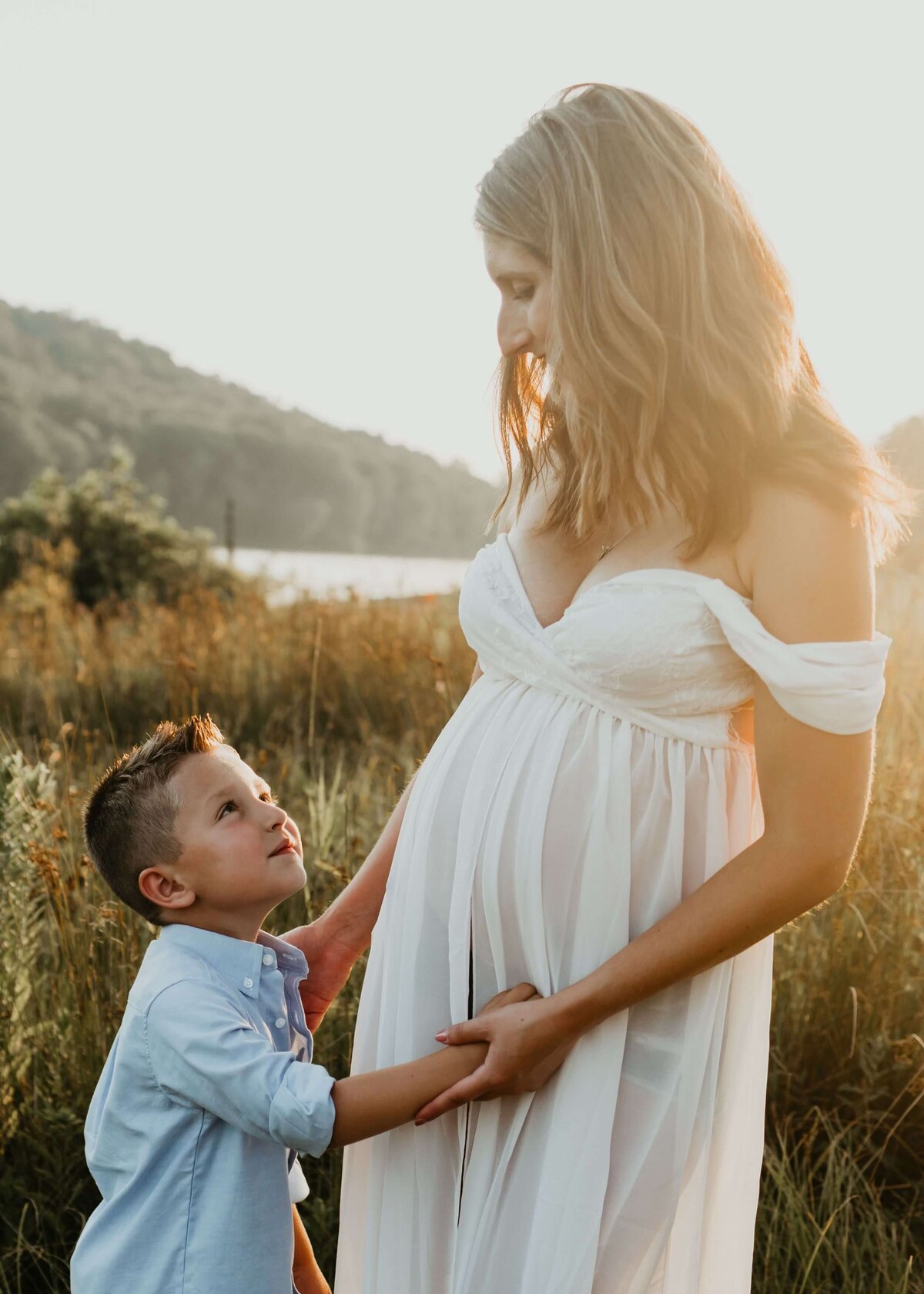 Capture the beauty of a pregnant woman and her son standing in a field at sunset with the expertise of a Pittsburgh maternity photographer.